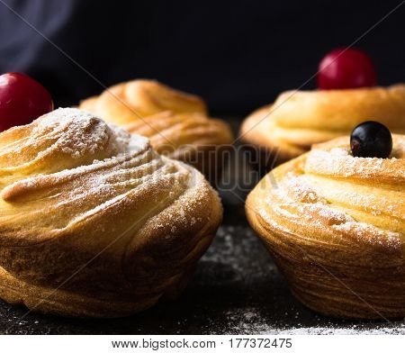 Cruffin - Buns from yeast dough. Dark graunge background. Mystical light. cinnamon craffin (cinnabon) (mix of croissant and muffin)
