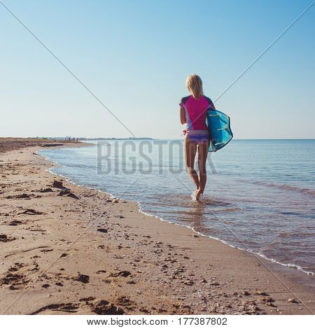Surfer girl on the beach waiting for waves