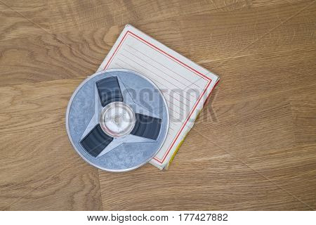 Vintage magnetic audio tape, reel to reel type, paper box on the grunge wooden floor