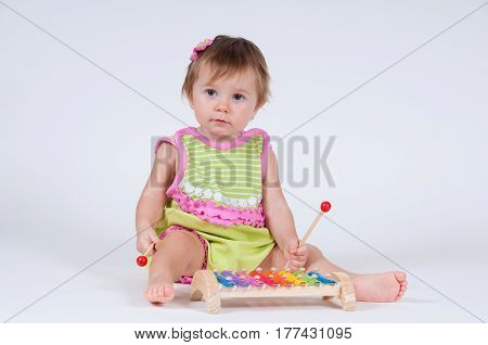 Girl with excitement playing on a xylophone isolated on white.