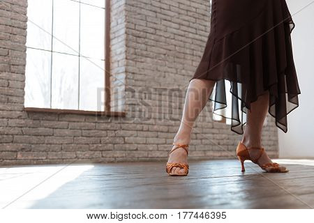 Step by step. Confident gifted aging woman dancing in the ballroom while performing dancing steps and having training session