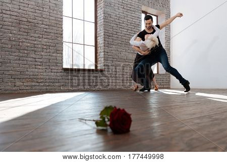 Performing flexible steps together. Skilled flexible experienced dance instructor teaching senior woman tango while dancing and learning new step