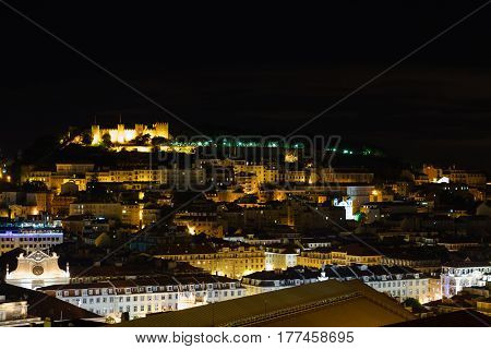 Cityscape of Lisbon, Portugal, with the Sao Jorge Castle seen from Miradouro Sao Pedro de Alcantara at night.