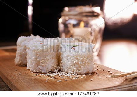 Japanese food sushi roll with crab sesame seeds cucumber cheese on a wooden board svea in the background