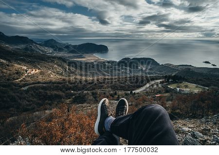 Men's legs in the brown shoes lying on the mountain on the mountain scape background