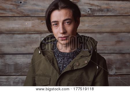 Handsome man wearing green jaket and torn jeans in wooden rural house interior. Processed with VSCO k2 preset