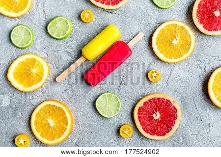 fresh citrus slices with fruit popsicles on stone table background top view pattern