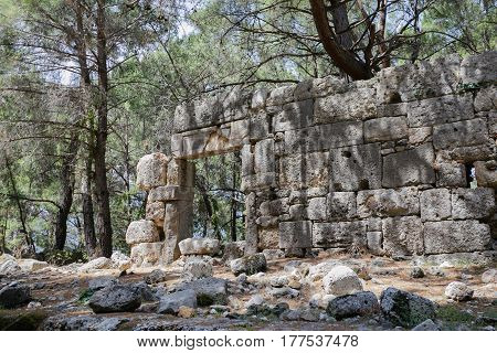Fragment of old building with door frame in ancient city of Phaselis located in pine forest iln Antalya province of Turkey