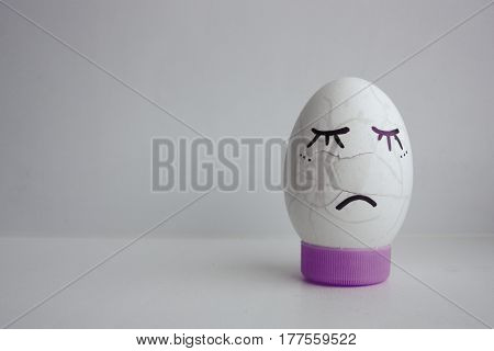 The egg is funny with the face on the stand. Concept: the pain broke cracked. Photo for your design on a white background