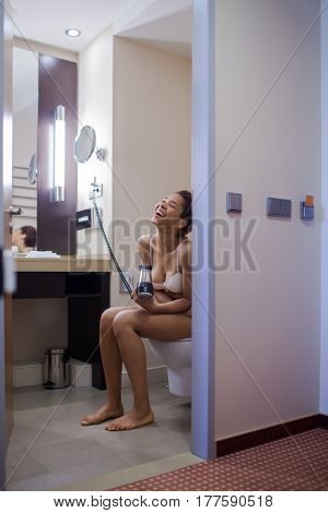 Young Woman Blow Drying Hair In Bathroom