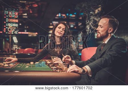 Upper class friends gambling in a casino.