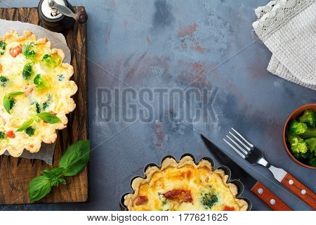 Homemade quiche tart with red fish salmon broccoli basil seasonings and cheese on a gray stone background. Selective focus.Top view.