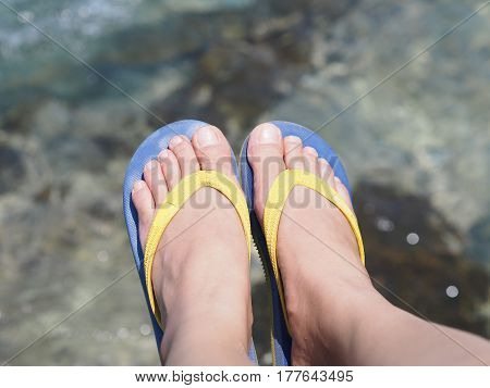 Selfie bare feet wearing colorful sandal over sea water background