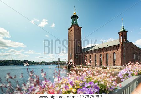 View on city hall (stadshuset) building in Stockholm Sweden Scandinavia Europe. Foreground with flowers and blue cloudy sky as background.