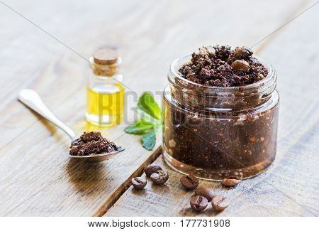 Organic scrub from ground coffee ith oil in cosmetic set on wooden white table background