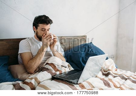 Bearded Man Lying In Morning Bed With Coffee Or Tea Cup