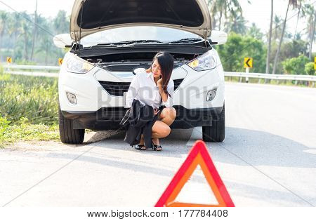 Business woman with a broken car calling for assistance