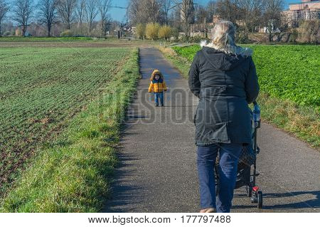 Grandmother with grandson while walking and pushes a baby carriage.