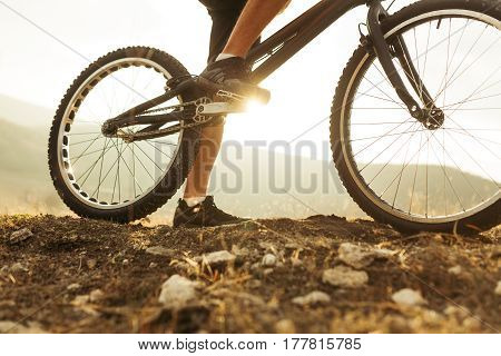 Horizontal outdoors shot of legs of sportsman on a trial bicycle treadle. Horizontal outdoors shot.
