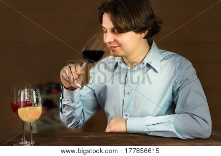 A photo of an enologist tasting wine at a winery, smiling, with more glasses in front of him