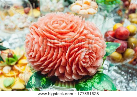 beautiful watermelon carving on the table on wedding candybar. a lot of desserts