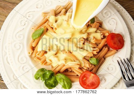 Adding cheese sauce to delicious pasta, closeup