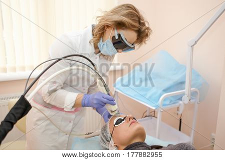 Therapist Beautician Makes A Laser Rejuvenation For The Woman By Apparatus In A Beauty Salon.