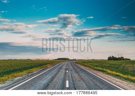 Curved Asphalt Country Open Road Through Spring Fields And Meadows In Sunny Evening. Landscape In Belarus Or European Part Of Russia In Early Summer Season At Sunny Day