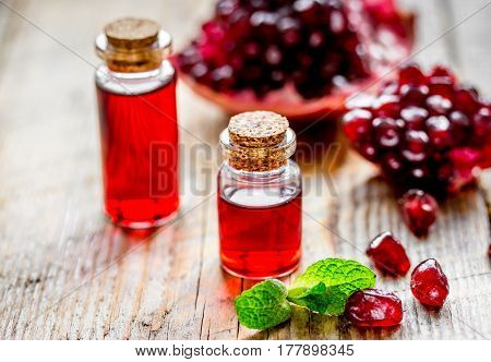 sliced pomegranate and extract in glass on wooden background close up