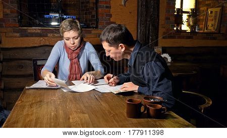 Businessman and businesswoman business partners discussing and signing contract in a restaurant cafe.
