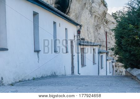 Rocky road with a number of houses at the foot of the mountain. A number of the houses with whitewashed walls, view of rural, mountains areas.