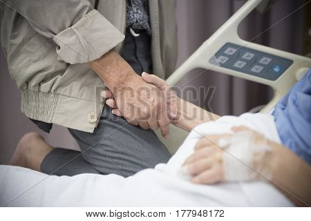 An old women Sick patient lying on bed holding her husband hand in hospital for medical background