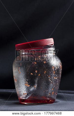 Empty fruity jam jar on table on dark background