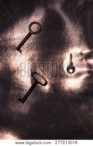 Two Keys With Round Base And One Key With Rectangular Base Scattered In A Mess On Purple Background
