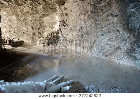 Salt Wall Near A Small Lake Inside A Salt Mine In Romania At Ocnele Mari.