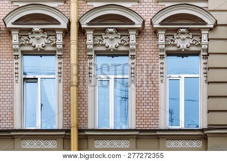 Three Rectangular Windows With An Arch And A Bas-relief On The Background Of A Wall Of Pink Brick. F