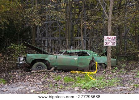 Old Car Left To Rot Beside A Wooden Roller Coaster In An Abandoned Amusement Park
