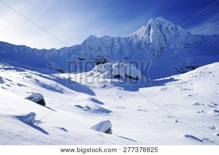 Bucura II Peak,  2372m. Winter alpine landscape in National Park Retezat, Carpathians, Romania, Europe. Snow covered moutains scenery