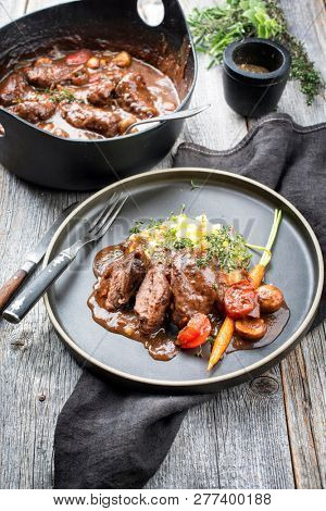 Traditional German braised pork cheeks in brown sauce with mushroom and mashed potatoes as closeup on a modern design plate 
