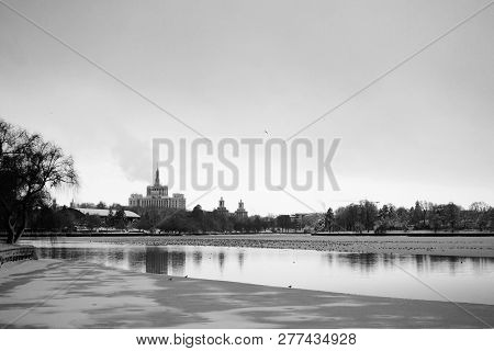 The City In Winter Viewed Over The Half Frozen Lake In Herastrau Park In Black And White.