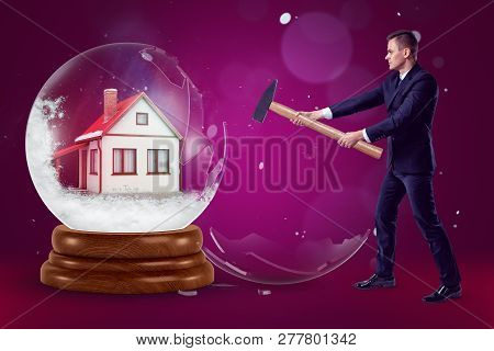 A Businessman With A Hammer In His Hands Crashing A Crystal Ball With A Little House Inside On A Pur