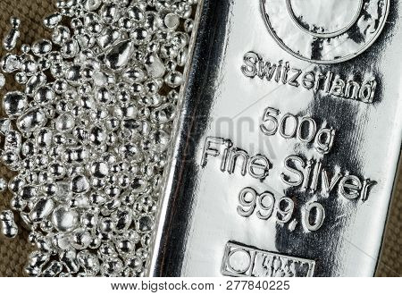 A Silver Bar And A Pile Of Silver Grains On The Background To The Coarse Texture Of The Textile.