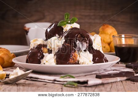 Chocolate Profiteroles With Whipped Cream On White Dish.