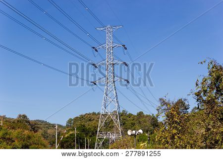 High Voltage Transmission Towers With Mountain Background And Blue Sky