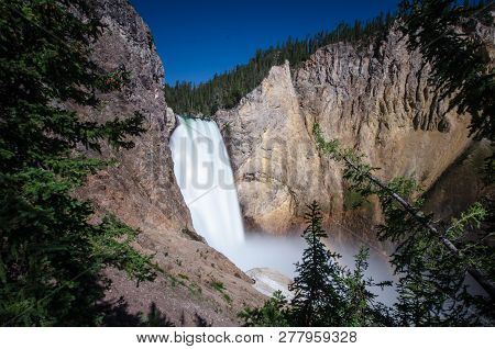 Yellowstone Falls Waterfall As Seen From The Uncle Tom's Trail With A Small Rainbow On A Sunny Day