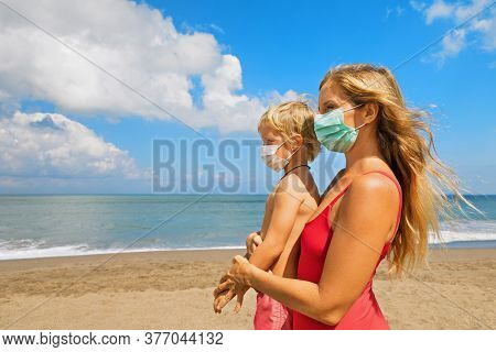 Mother Put Medical Mask On Child On Sea Beach. New Rules To Wear Cloth Face Covering At Public Place