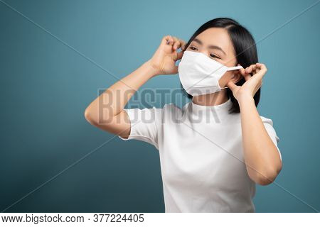 Asian Woman Wearing Protective Mask For Protection From Virus And Disease Isolated On Blue Backgroun
