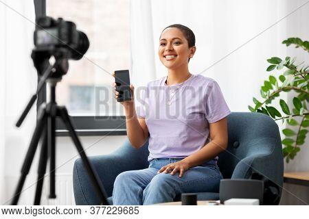 blogging, videoblog and people concept - happy smiling african american female video blogger with smartphone camera videoblogging at home
