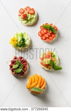 Puffed Rice Cakes With Different Toppings Friuts And Vegetables On White Background, Flat Lay. Vegan