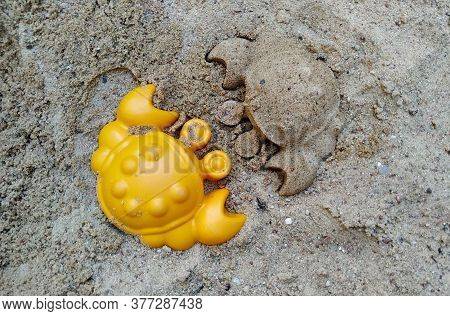 Orange Figurine Of Crab And A Crab Made Of Sand In The Sandbox.
